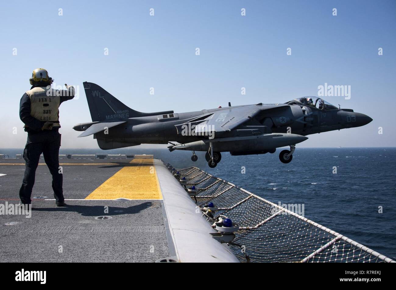 EAST CHINA SEA (April 3, 2017) Aviation Boatswain's Mate (Handling) Airman Matthew Titus, from St. Louis, Mo., directs the launch of an AV-8B Harrier, assigned to the Tomcats of Marine Attack Squadron (VMA) 311, from the flight deck of the amphibious assault ship USS Bonhomme Richard (LHD 6). Bonhomme Richard, flagship of the Bonhomme Richard Expeditionary Strike Group, with embarked 31st Marine Expeditionary Unit, is on a routine patrol, operating in the Indo-Asia-Pacific region to enhance warfighting readiness and posture forward as a ready-response force for any type of contingency. Stock Photo