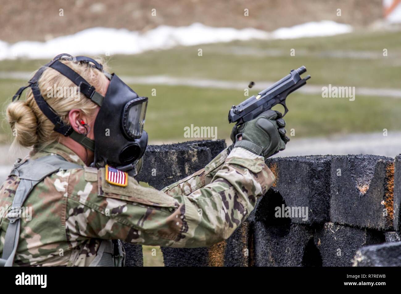 Spec. Courtney Natal fires the M-9 pistol while wearing a protective mask during the stress shoot lane, combining physical tests and shooting events during the New York Army National Guard  Best Warrior Competition at Camp Smith Training Site March 30, 2017. The Best Warrior competitors represent each of New York's brigades after winning competitions at the company, battalion, and brigade levels. At the state level they are tested on their physical fitness, military knowledge, endurance, marksmanship, and land navigation skills. The two winners of the competition, one junior enlisted and one N Stock Photo