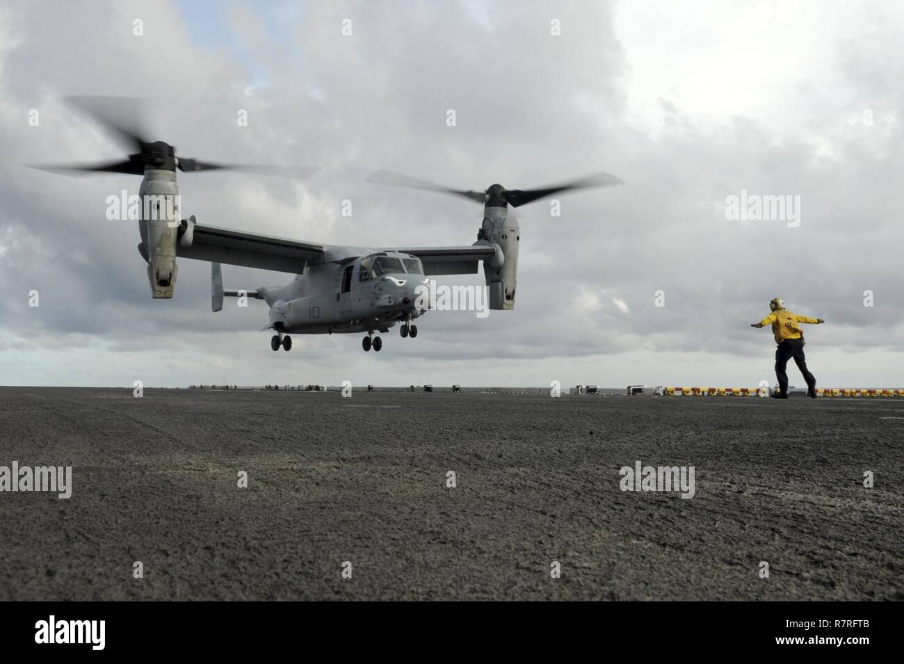 SOUTH CHINA SEA (April 3, 2017) Aviation Boatswain’s Mate (Handling) 3rd Class Skyler Campbell, from Castlewood, Va., signals for an MV-22B Osprey, assigned to the Ridge Runners of Marine Medium Tiltrotor Squadron (VMM) 163, to land on the flight deck of the amphibious assault ship USS Makin Island (LHD 8). Makin Island, the flagship for the Makin Island Amphibious Ready Group, with the embarked 11th Marine Expeditionary Unit, is operating in the Indo-Asia-Pacific region to enhance amphibious capability with regional partners and to serve as a ready-response force for any type of contingency. Stock Photo