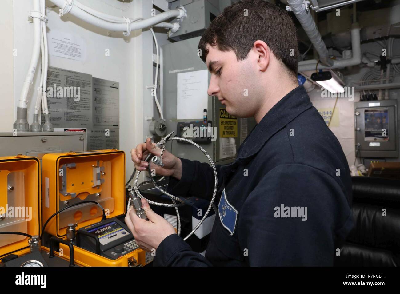 5TH FLEET AREA OF OPERATION (March 30, 2017) Aviation Electronics Technician Airman Andrew Decataor Wear, performs maintenance on an automated pressure calibrator in the calibration shop aboard the amphibious assault ship USS Bataan (LHD 5). The ship is currently deployed with the Bataan Amphibious Ready Group in support of maritime security operations and theater security cooperation efforts in the U.S. 5th Fleet area of operations. Stock Photo