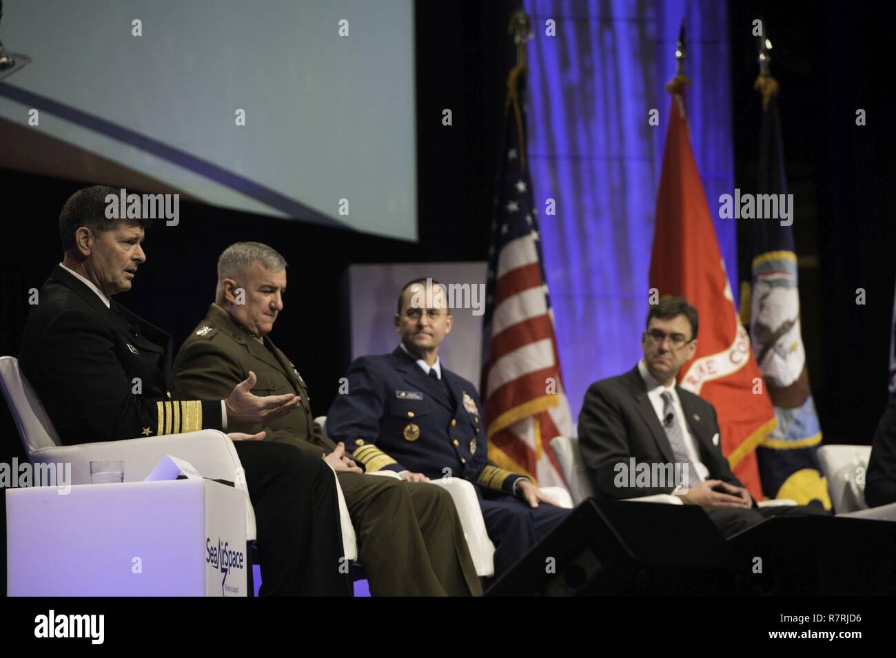 NATIONAL HARBOR, Md. (April 3, 2017) Vice Chief of Naval Operations (VCNO) Vice Adm. William Moran, left, speaks at the 2017 Sea, Air and Space Exposition. Moran was joined by a panel including Assistant Commandant of the U.S. Marine Corps Gen. Glenn Walters, Vice Commandant of the U.S. Coast Guard Adm. Charles Michel, and Joel Szabat, executive director of Maritime Transportation, to discuss a “Sea Services Update” regarding today's maritime environment. The annual event, founded in 1965, is the largest maritime exposition in the U.S. and brings together key military decision makers, U.S. def Stock Photo