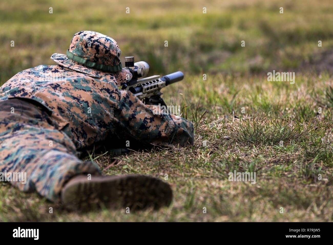A Marine aims down the scope of an M40A6 rifle during an urban sniper course at Camp Lejeune, N.C., March 30, 2017. The Marines practiced engaging targets from unknown distances to maintain their skills on the weapon. The course, taught by Expeditionary Operations Training Group, includes Marines from 2nd Battalion, 6th Marine Regiment, 2nd Reconnaissance Battalion and School of Infantry-East. Stock Photo