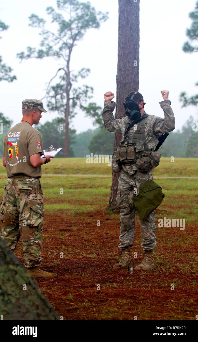 A U.S. Army National Guard Sergeant from the 2nd Battalion, 124th Infantry Regiment quickly dons his Field Protection Mask during the patrol testing phase for the Expert Infantry Badge qualification at Camp Blanding Training Center, Starke, Fla. on April 5th, 2017. The protective mask helps Soldiers combat threatening air born chemicals. Stock Photo