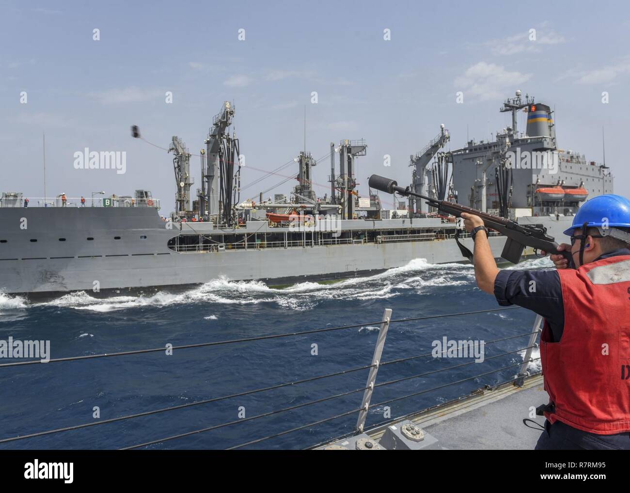 ARABIAN SEA (April 3, 2017) Fire Controlman 2nd Class Christopher Stangl fires a shot line from the guided-missile destroyer USS Mahan (DDG 72) to the Military Sealift Command fleet replenishment oiler USNS Walter S. Diehl (T-AO 193) during a replenishment-at-sea. Mahan is part of the George H.W. Bush Carrier Strike Group deployed in the U.S. 5th Fleet area of operations in support of maritime security operations designed to reassure allies and partners, preserve the freedom of navigation and the free flow of commerce in the region. Stock Photo