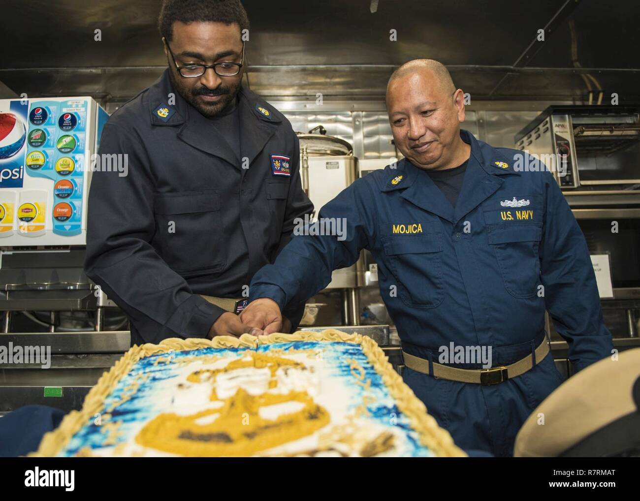 WATERS SURROUNDING THE KOREAN PENNINSULA (April 1, 2017) Chief Operations Specialist Gerald Crawford and Chief Machinist Mate Lyndon Mojica cut a ceremonial cake in celebration of the 124th birthday of the chief petty officer rank on the messdecks of Arleigh Burke-class guided-missile destroyer USS Barry (DDG 52).  Barry is on patrol in the U.S. 7th Fleet area of operations in support of security and stability in the Indo-Asia-Pacific region. Stock Photo