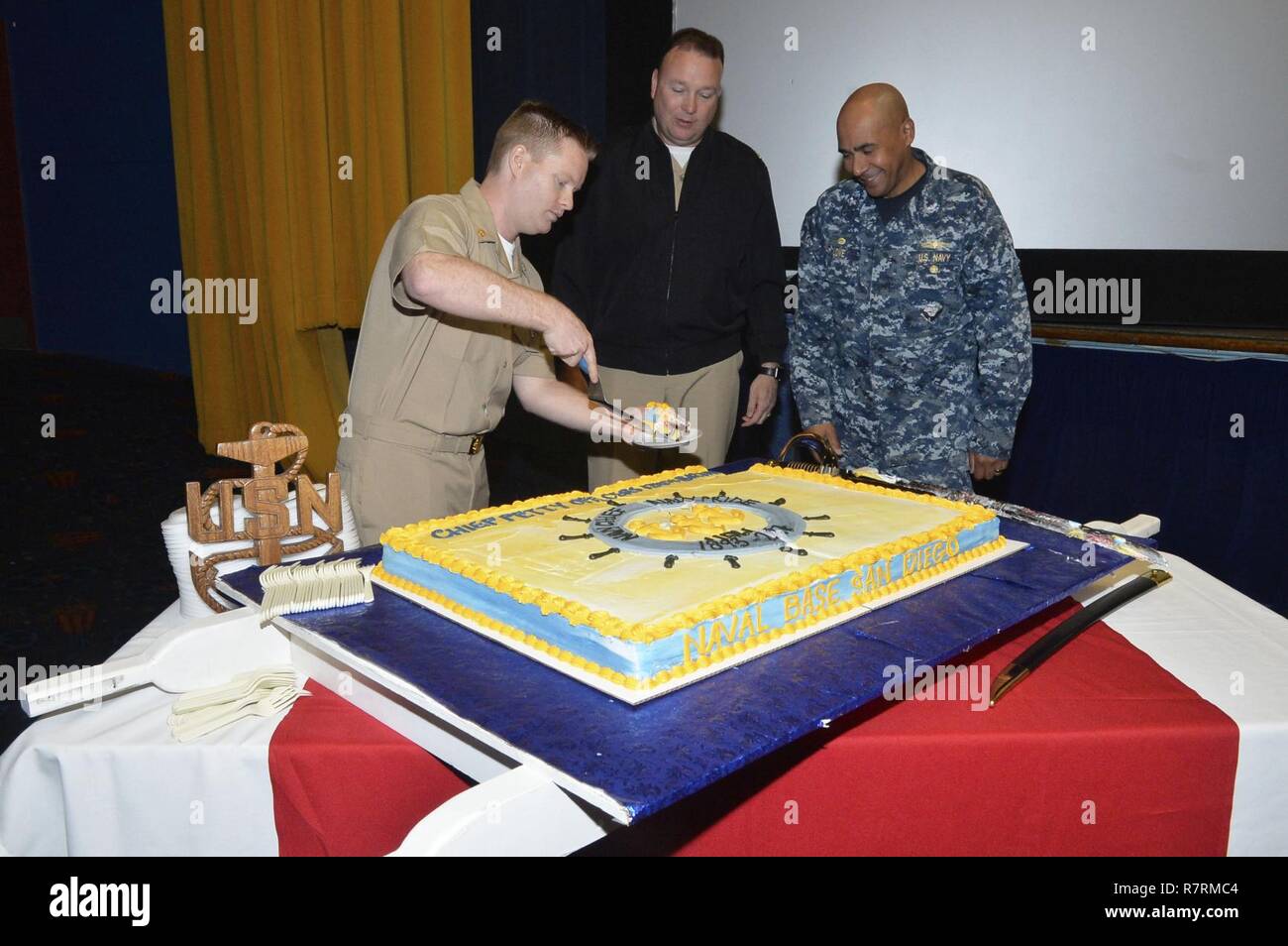 SAN DIEGO (April 3, 2017)  The youngest Chief Petty Officer from Naval Base San Diego Chief Quartermaster Colin Lalor serves a slice of cake to Commanding Officer Capt. Roy Love, right, and Command Master Chief Matt Ruane in celebration of the 124th birthday of the chief petty officer rank at the base theater. Stock Photo