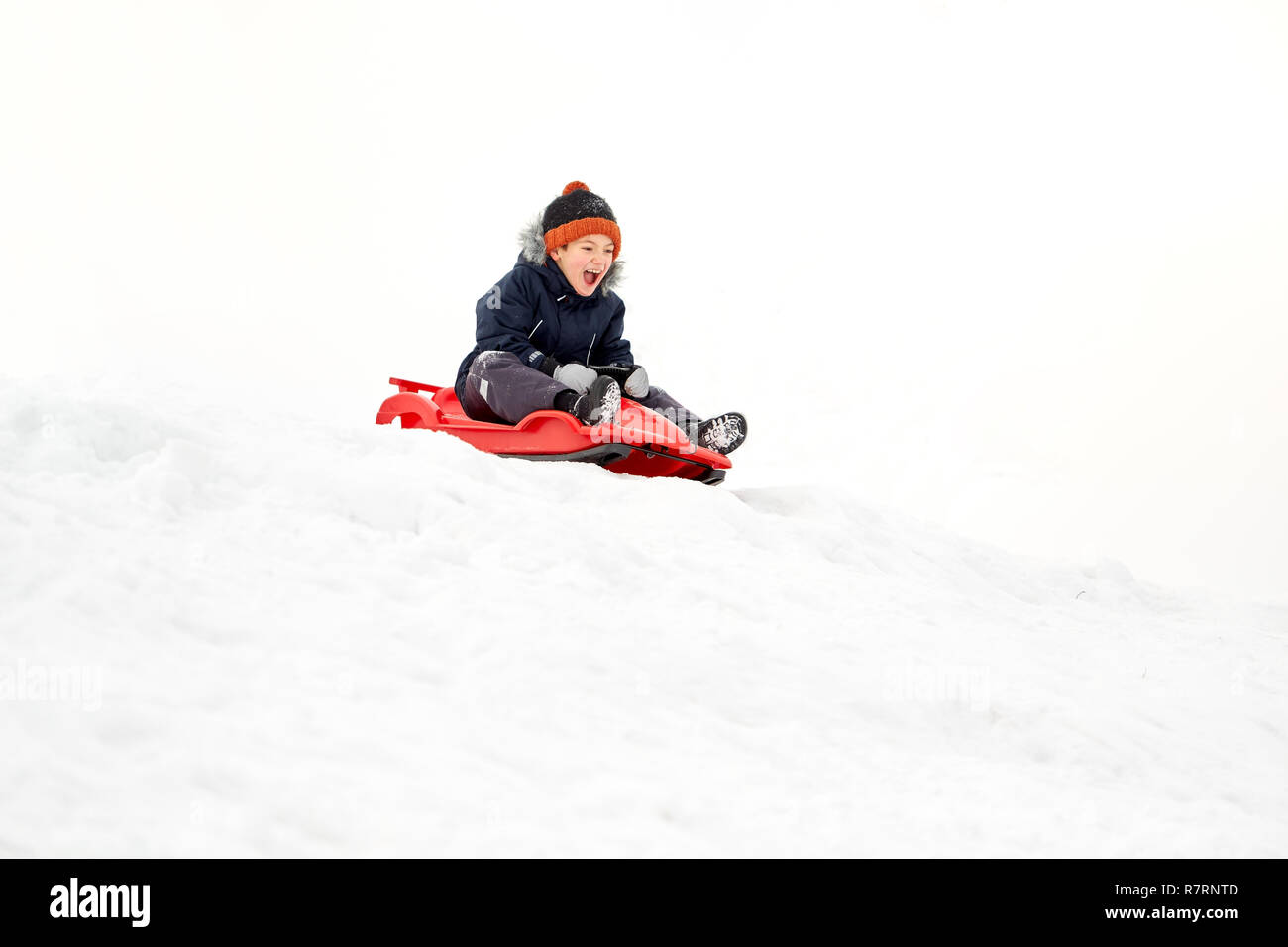 happy boy sliding on sled down snow hill in winter Stock Photo Alamy
