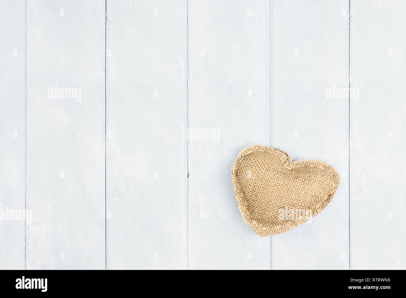 St Valentine's Day burlap heart over wooden background with room for copy space shot from above. Stock Photo