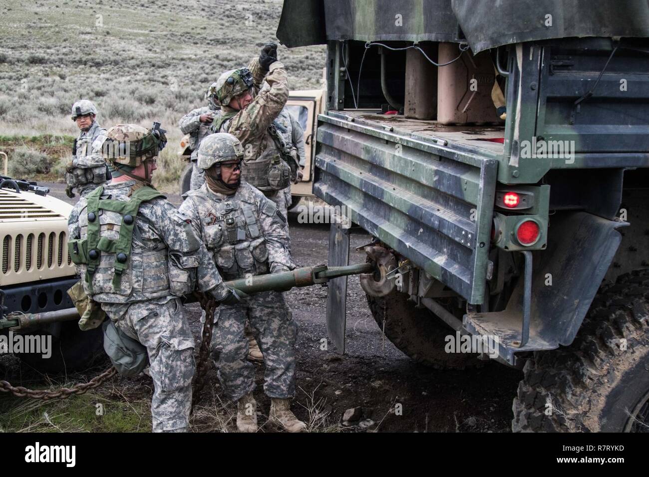 308th Brigade Support Battalion, 17th Field Artillery Brigade’s, 1st Lt. Sheldon Helm and Sgt. 1st Class Abraham Rivera-Perez hold a tow bar up as Sgt. Skyler Smith, also of 308th BSB, directs the Light Medium Tactical Vehicle so that the tow bar can be locked into place during a training evaluation at Yakima Training Center, Wash., April 8, 2017. 308th BSB is at YTC to conduct evaluations on how well the soldiers are being trained on their combat operation tasks. Stock Photo