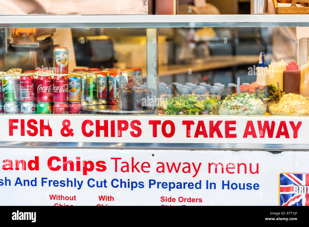 London, UK - September 12, 2018: Greasy street food, fried french fries chips take away menu restaurant sign, soft drinks in SoHo on window display cl Stock Photo