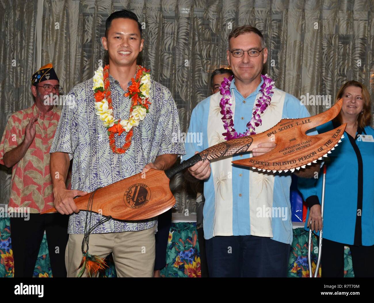 Petty Officer 2nd Class Scott Lee, a boatswain’s mate stationed at Coast Guard Sector Honolulu, receives a battle ax from Master Chief Petty Officer, command master chief, Coast Guard 14th District during the Regional Enlisted Person of the Year Recognition Dinner at Hickam Officers Club, April 5, 2017. Lee was recognized as the Reserve Enlisted Person of the Year for outstanding performance of duty and contribution to the service, unit and community. Stock Photo