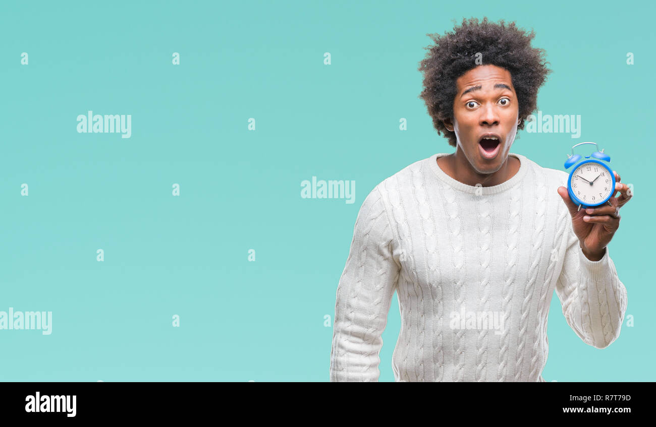 Afro american man holding vintage alarm clock over isolated background