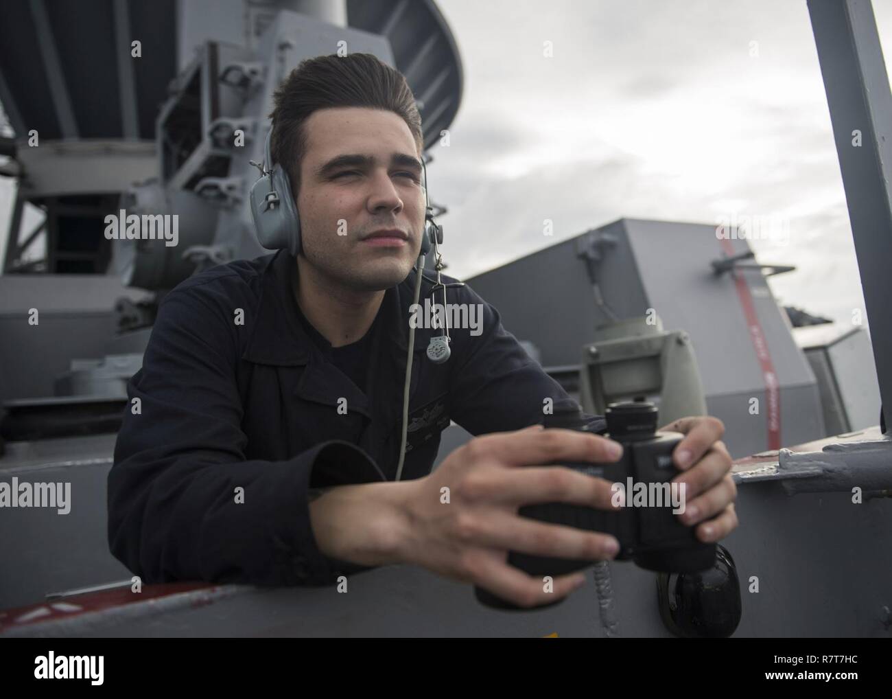 SOUTH CHINA SEA (April 4, 2017) Seaman Wesley Falcoa, from Aurora, Colo., scans the ocean for contacts while standing forward lookout aboard the amphibious assault ship USS Makin Island (LHD 8). Makin Island, the flagship for the Makin Island Amphibious Ready Group, with the embarked 11th Marine Expeditionary Unit (11th MEU), is operating in the Indo-Asia-Pacific region to enhance amphibious capability with regional partners and to serve as a ready-response force for any type of contingency. Stock Photo