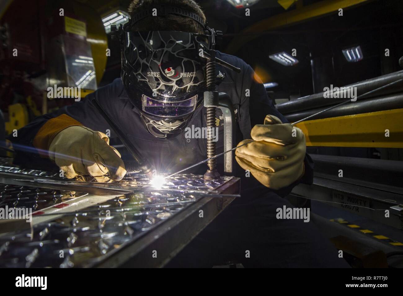 ATLANTIC OCEAN (April 5, 2017) Hull Technician 3rd Class Justin Farrar, from Brownstown, Mich., tack welds a door cover aboard the aircraft carrier USS Dwight D. Eisenhower (CVN 69). The ship and its carrier strike group are underway conducting a sustainment exercise in support of the Optimized Fleet Response Plan. Stock Photo