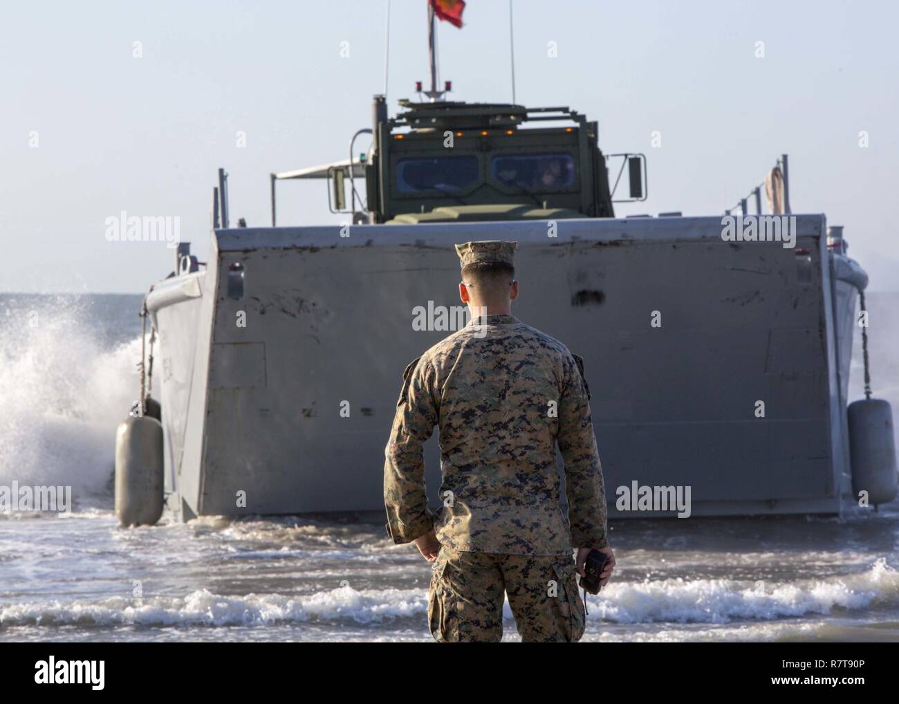 First Lt. James A. Teasdale supervises an Army Landing Craft Mechanized-8 boat carrying Marine personnel and equipment during a beach operations group exercise at Onslow Beach, N.C., March 30, 2017. The training provided Marines the opportunity to work with Soldiers as part of field exercise Bold Bronco 17. Teasdale is platoon commander with Combat Logistics Battalion 8, 2nd Marine Logistics Group. Stock Photo