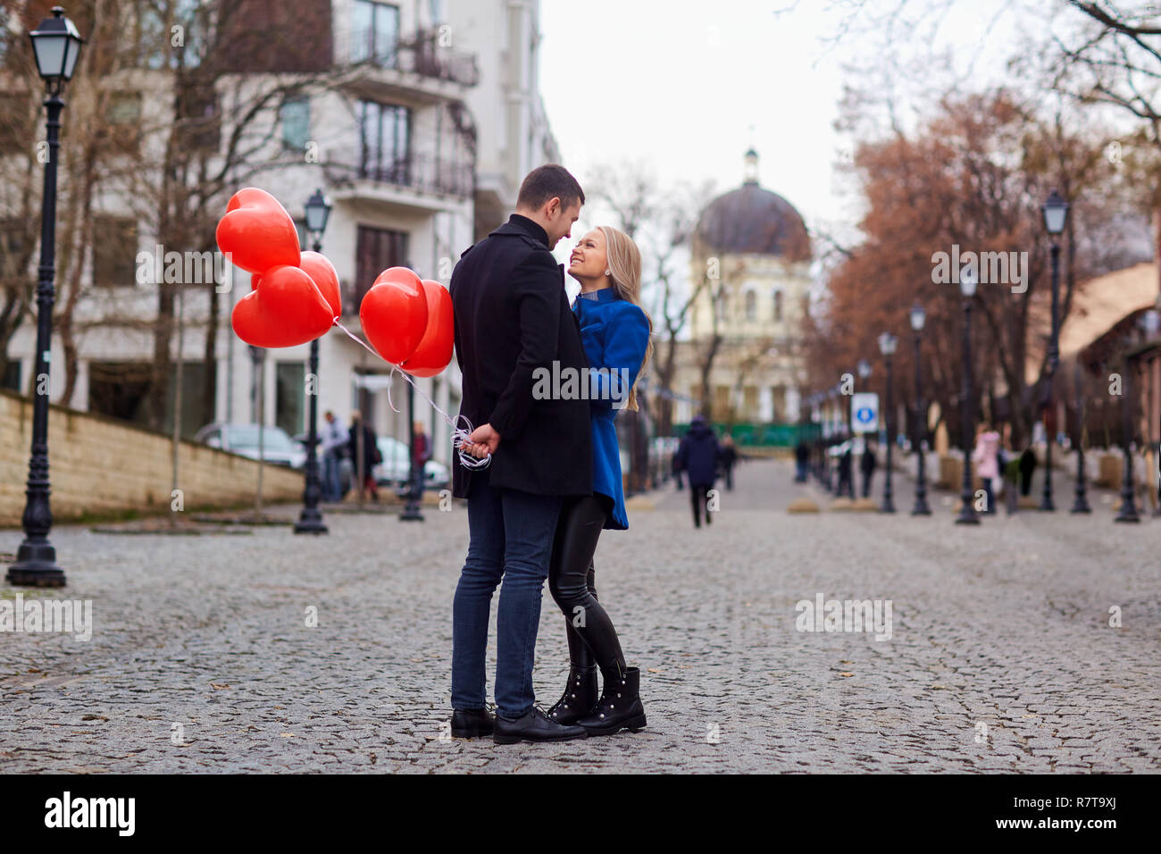 A loving couple in a coat with balloons hearts in hands Stock Photo - Alamy