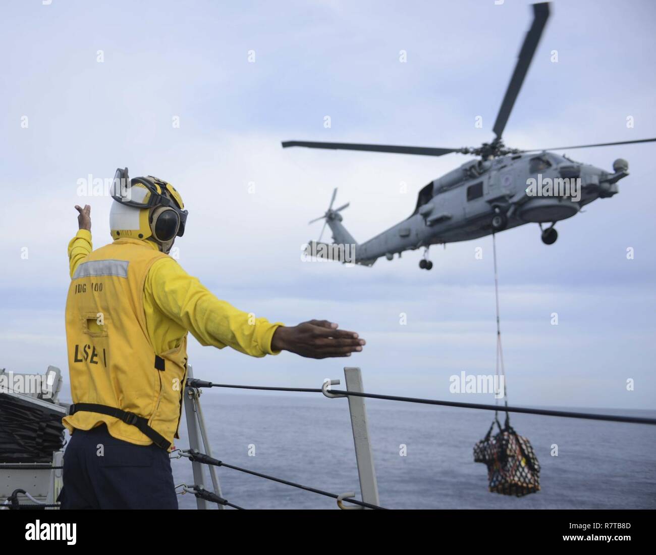 pacific-ocean-april-6-2017-boatswains-mate-3rd-class-brooks-best-from-raleigh-nc-directs-an-mh-60r-seahawk-helicopter-assigned-to-the-magicians-of-helicopter-maritime-strike-squadron-hsm-35-during-a-vertical-replenishment-vertrep-aboard-the-arleigh-burke-class-guided-missile-destroyer-uss-kidd-ddg-100-while-underway-conducting-a-composite-training-unit-exercise-comptuex-with-the-nimitz-carrier-strike-group-in-preparation-for-an-upcoming-deployment-comptuex-tests-the-mission-readiness-of-the-strike-groups-assets-through-simulated-real-world-scenarios-and-their-ability-to-pe-R7TB8D.jpg