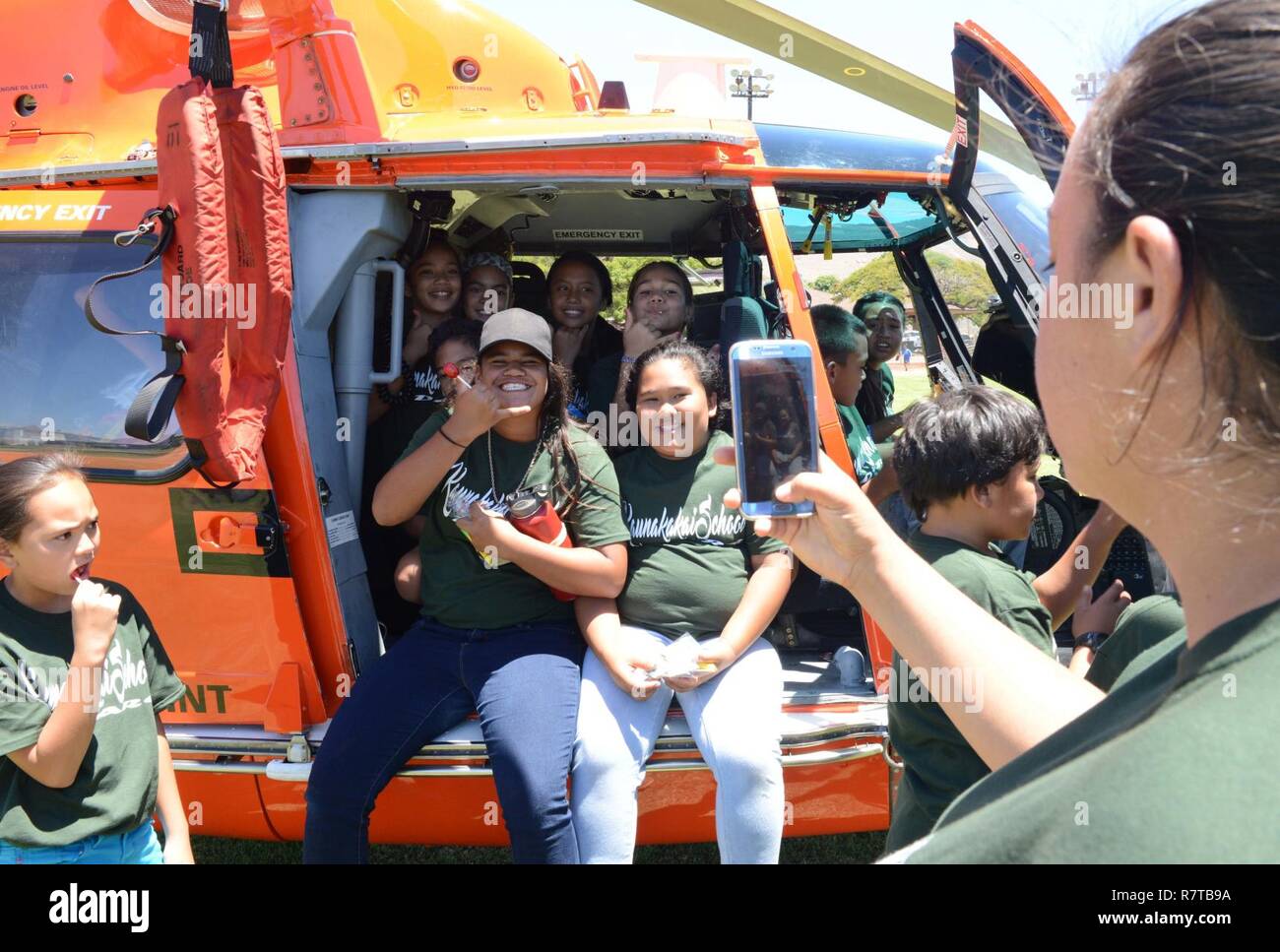 Students smile for a photo in an MH-65 Dolphin Helicopter from Coast Guard Air Station Barbers Point, Oahu, during a D.A.R.E. event for Kualapuu Public Charter School children at Kaunakakai Ball Park, Molokai, April 7, 2016. The rally was held to educate the children on the dangers of drugs and also included demonstrations from Coast Guard Air Station Barbers Point, National Guard, Maui Police Department, Maui County Fire Department, Hawaii Department of Land and Natural Resources and several other agencies. Stock Photo