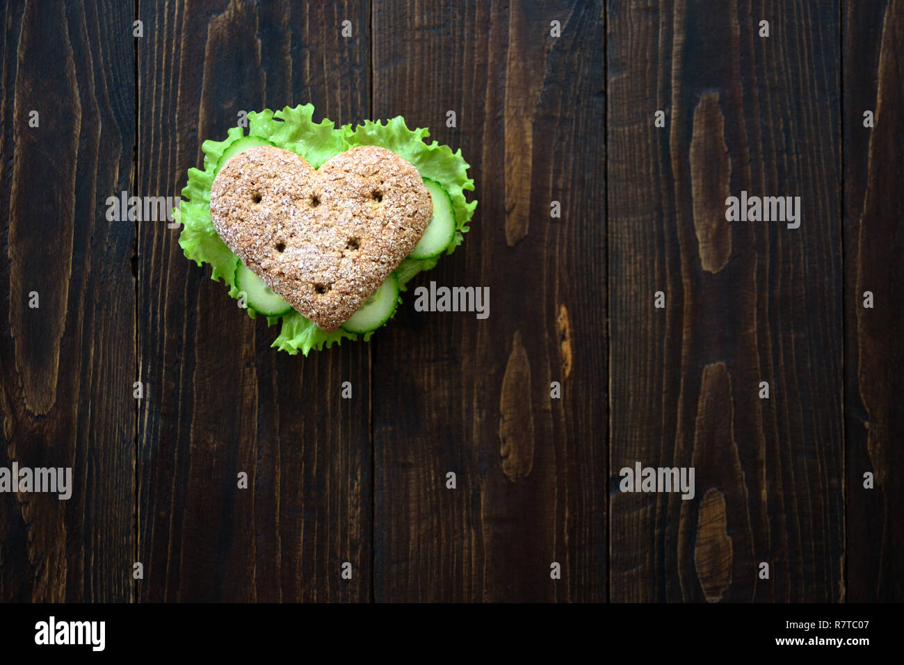 Healthy heart shape sandwich with salad and cucumbers. Dieting concept. Wooden background Stock Photo