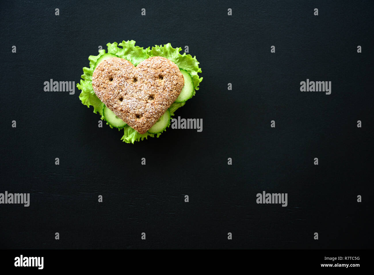 Healthy heart shape sandwich with salad and cucumbers. Dieting concept. Blackboard background Stock Photo