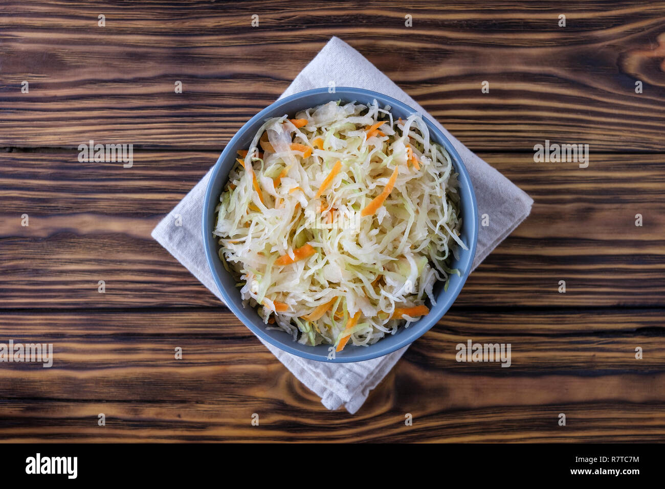 From above shot of ceramic bowl of palatable fermented cabbage on napkin on side of timber tabletop Stock Photo