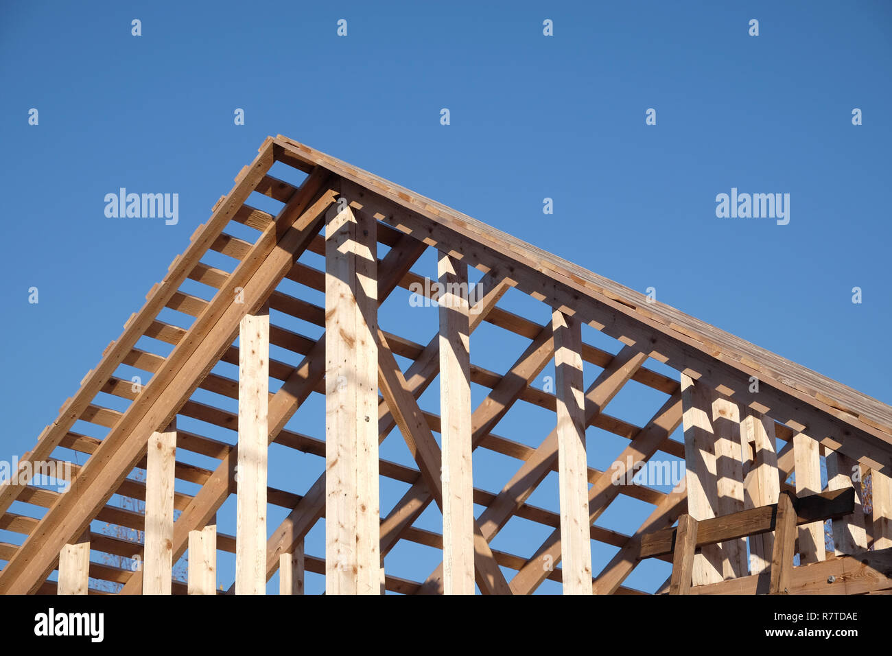 Process of wooden carcass house mounting ubder clear cloudless blue sky side view. Wooden country house construction Stock Photo