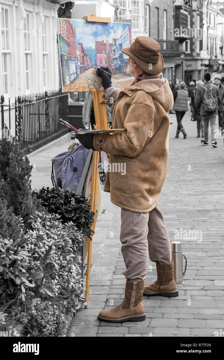 Artist painting street scene at High Street Winchester, Hampshire, UK in December - in monochrome with colour popping Stock Photo