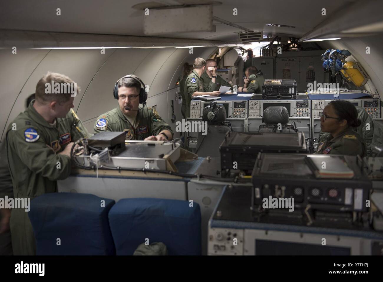 U.S. Air Force Airman 1st Class Favian Arteaga, 961st Airborne Air Control Squadron airborne surveillance technician (left), uses a communication system March 28, 2017, while flying in an E-3 Sentry over the Pacific Ocean. Airborne surveillance technicians make the initial identification of friend or foe aircraft and monitor their position. Stock Photo