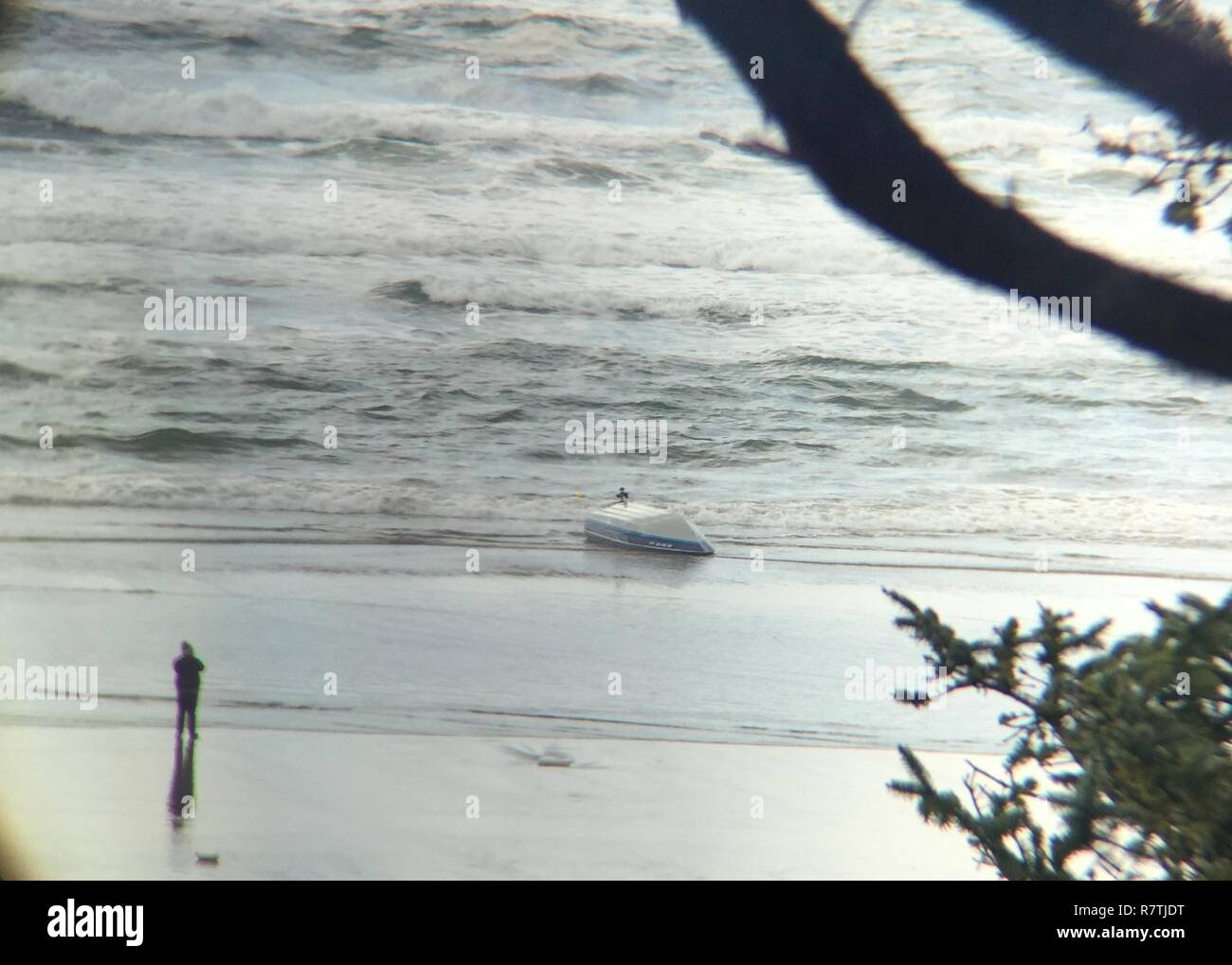 A boat sits on a beach near Yaquina Bay, Ore., after it overturned