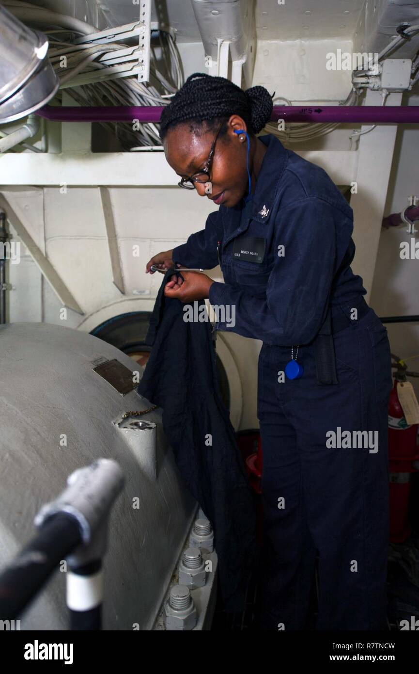 PACIFIC OCEAN (July 10, 2017) Gas Turbine Systems Technician Electrical 3rd Class Mercy Ngatia, a native of Nairobi, Kenya, uses a dipstick to inspect oil levels in the shaft alley during a routine walkthrough on board the amphibious assault ship USS America (LHA 6). America is currently embarked on its maiden deployment and is part of the America Amphibious Ready Group comprised of more than 1,800 Sailors and 2,600 Marines assigned to the amphibious dock landing ship USS Pearl Harbor (LSD 52), the amphibious transport dock ship USS San Diego (LPD 22) and America. Stock Photo