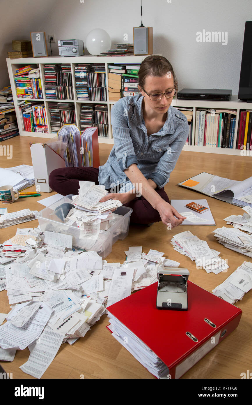 Woman sorting documents, records, invoices and receipts on the ground, for the tax return Stock Photo