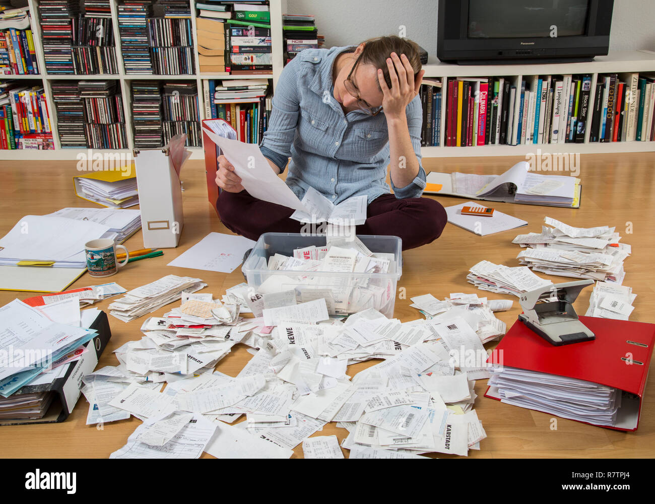 Woman sorting documents, records, invoices and receipts on the ground, for the tax return Stock Photo