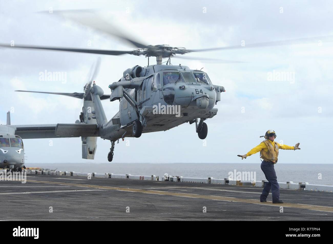 SOUTH CHINA SEA (April 3, 2017) Aviation Boatswain’s Mate (Handling) 2nd Class Christopher Diehl, from York, Pa., signals the crew of  an MH-60S Seahawk, assigned to the Blackjacks of Helicopter Sea Combat Squadron (HSC) 21, to take off from the flight deck of the amphibious assault ship USS Makin Island (LHD 8). Makin Island, the flagship for the Makin Island Amphibious Ready Group, with the embarked 11th Marine Expeditionary Unit, is operating in the Indo-Asia-Pacific region to enhance amphibious capability with regional partners and to serve as a ready-response force for any type of conting Stock Photo