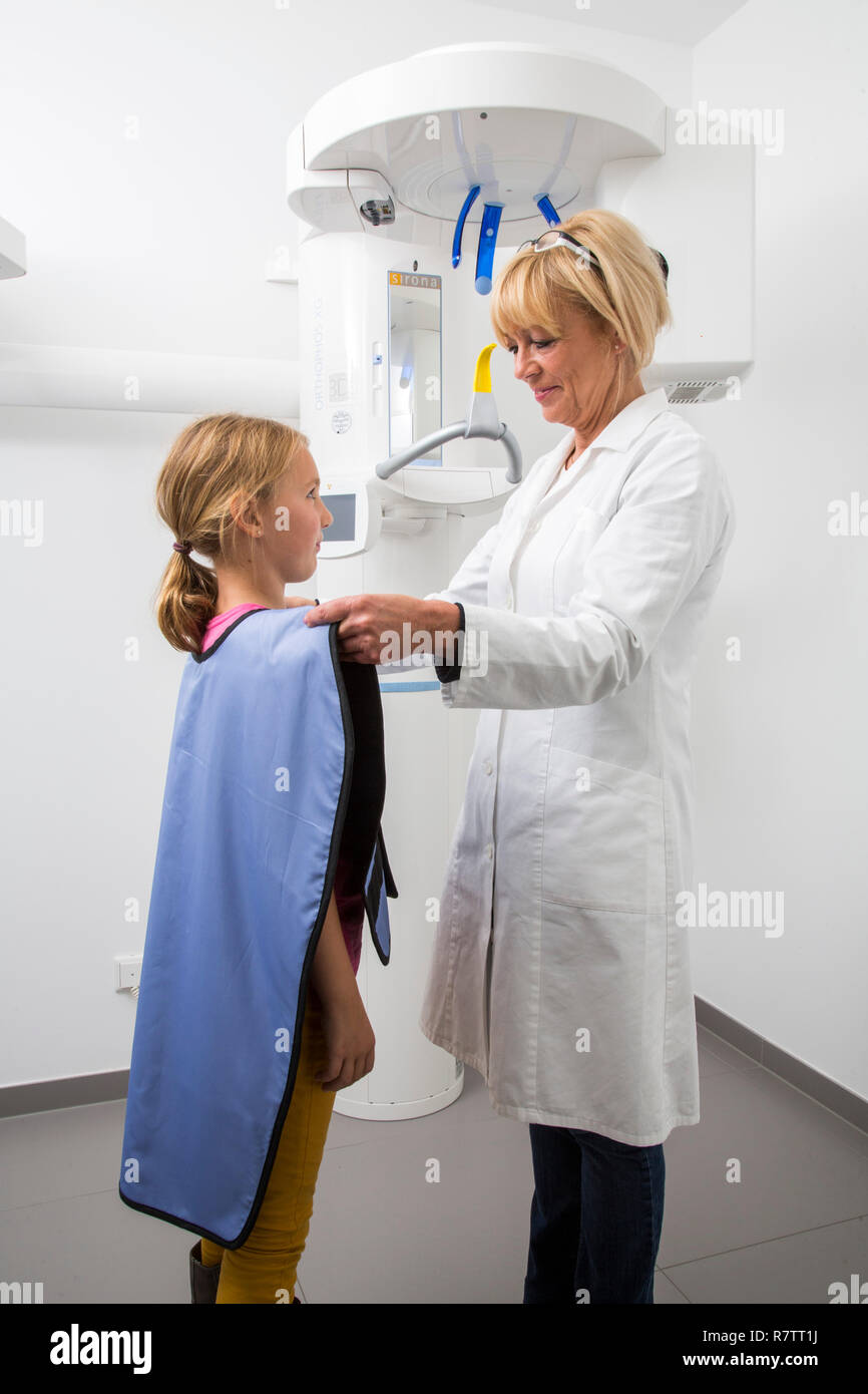 Girl being prepared for an x-ray of her teeth, wearing a lead vest as radiation protection, Germany Stock Photo