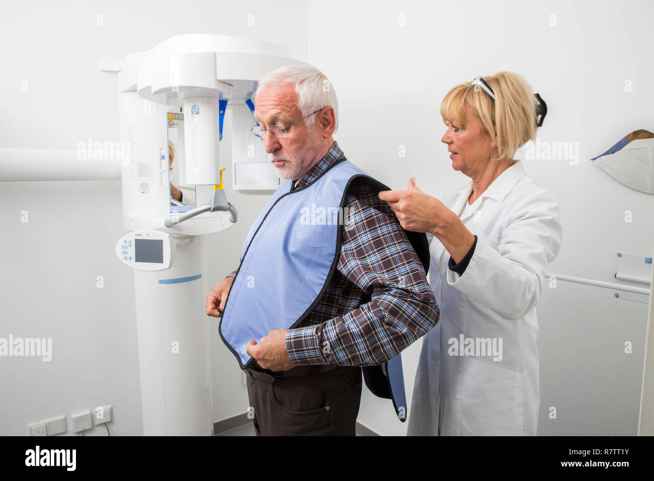 Man being prepared for an X-ray of his teeth, wearing a lead vest for protection from radiation, Germany Stock Photo