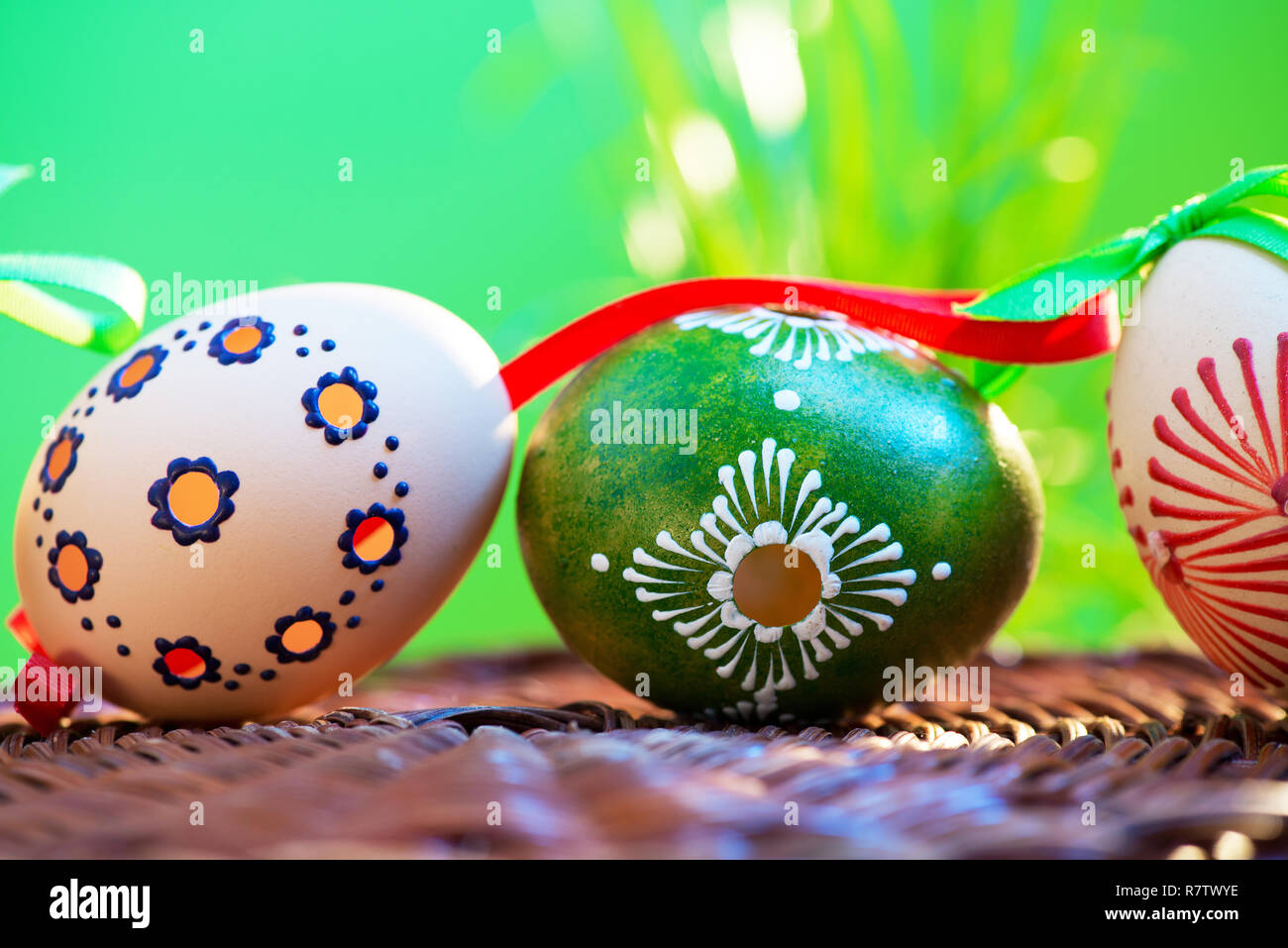 Painted easter eggs in the wicker basket in the grass. Stock Photo