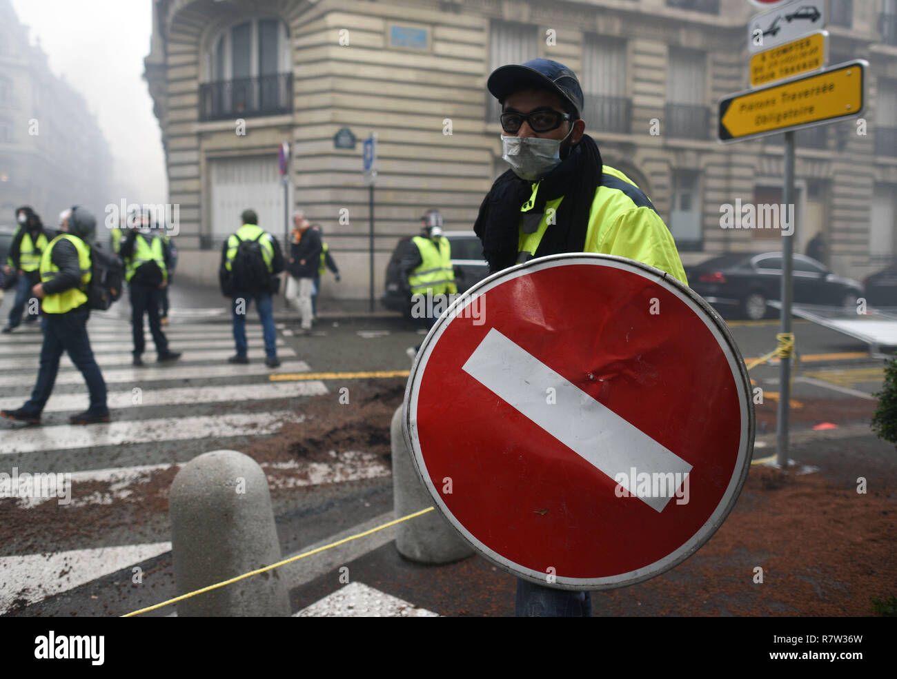 December 01, 2018 - Paris, France: A Yellow vest protester uses a road sign  as a shield in a side street near the Champs-Elysees avenue, where several  vehicles were burnt. Protesters clashed
