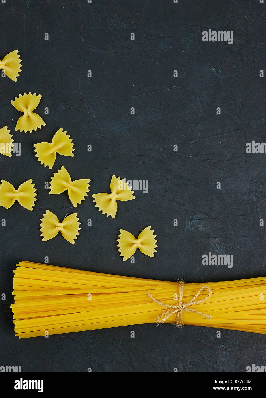 Uncooked pasta tied with a rope on concrete against black background. copy space. view from above. Stock Photo