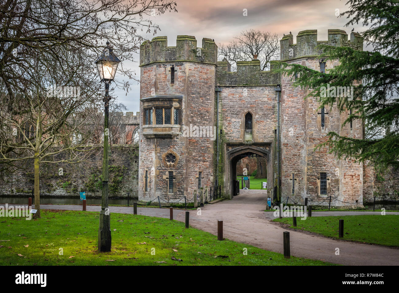 A streetlight flickers on as evening draws on at the entrance to the Bishop's Palace in Wells, Somerset, England. Stock Photo
