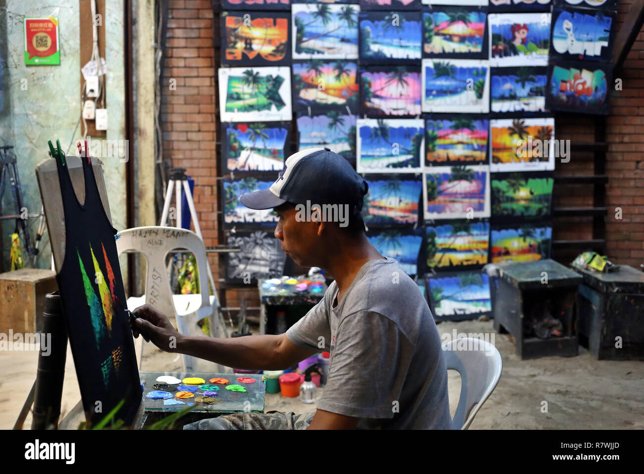 Boracay, Philippines. 09th Dec, 2018. A street artist paints T-shirts in a shop on the beach. The beaches of the island of Boracay were closed to the public for six months to stop the uncontrolled expansion of hotels, pollution and water pollution. After the reopening in October the tourists return to the main destination in the Philippines. The island was known in the past for its endless parties. Credit: Alejandro Ernesto/dpa/Alamy Live News Stock Photo