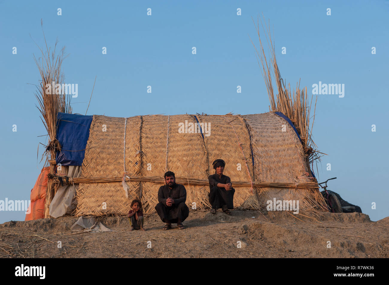 November 12, 2018 - Al-Chibayish, Marshes of Southern Iraq, Iraq - Hamar Marsh Arabs seen chilling next to their reed grass home in the Southern wetlands of Iraq.Climate change, dam building in Turkey and internal water mismanagement are the main causes of a severe drought in the southern wetlands of Iraq. Credit: John Wreford/SOPA Images/ZUMA Wire/Alamy Live News Stock Photo