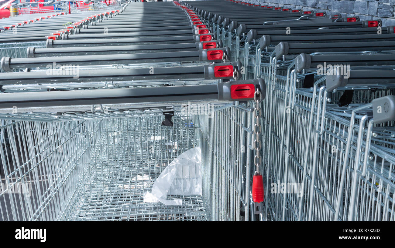 shopping trolleys, coin operated stacked outside a supermarket or food retail outlet. Stock Photo