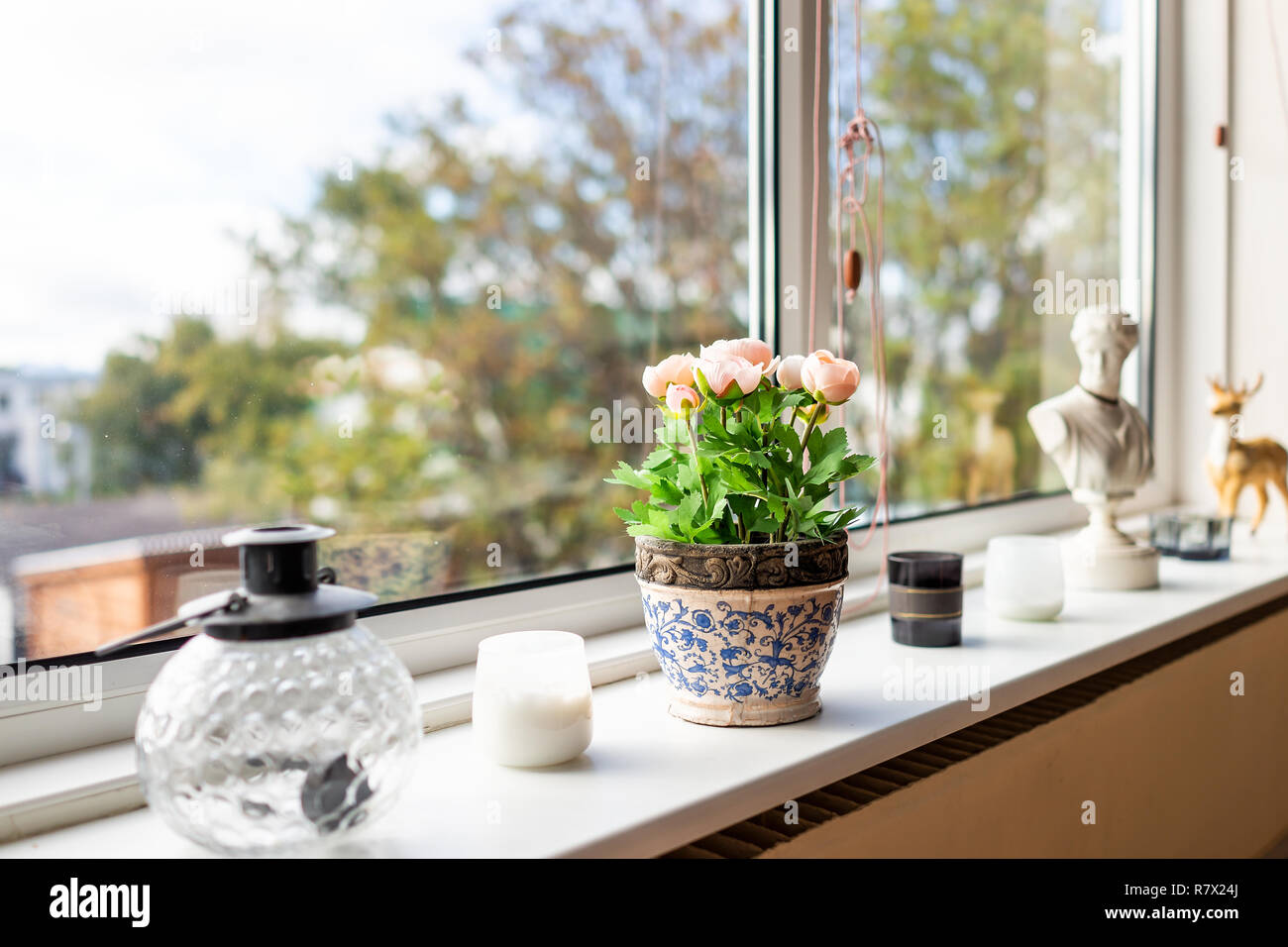 Modern house living room kitchen window decorations decor with candles, glass teapot, flowerpot flowers and sunlight, green plant staging home interio Stock Photo - Alamy