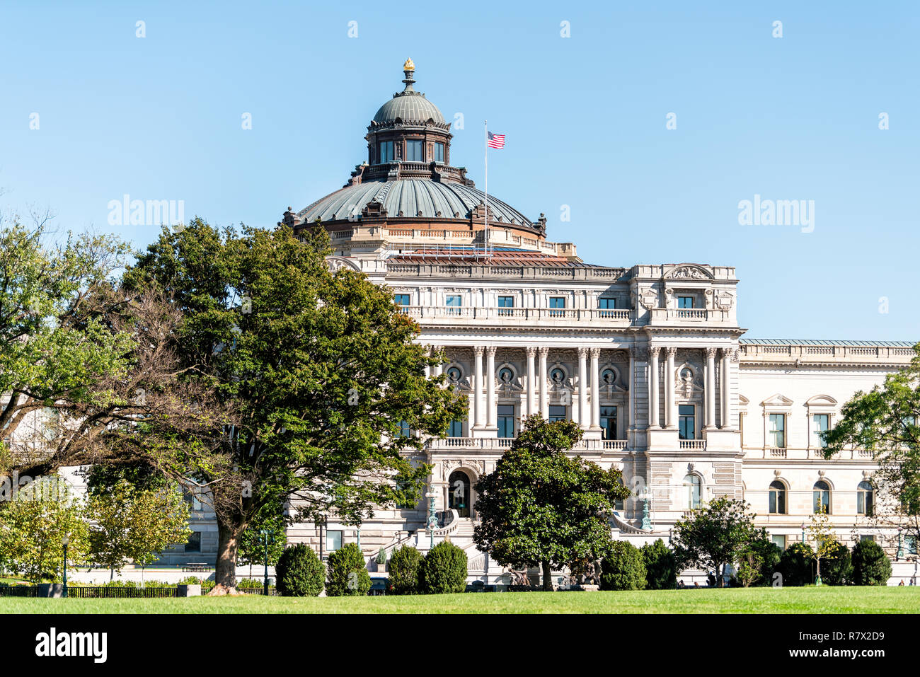 US National Library of Congress dome exterior with American flag waving in Washington DC, USA on Capital capitol hill, columns, facade landscape build Stock Photo