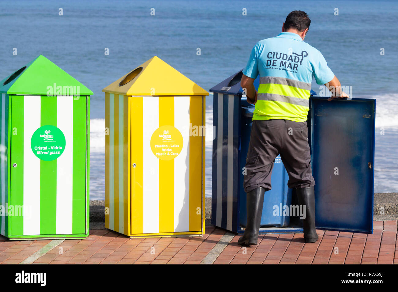 Council worker emptying colour coded waste bins for recycling plastic, paper, organic...on beach