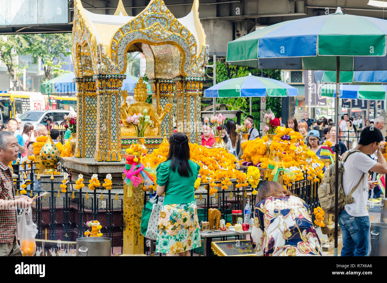 Locals praying in front of four-faced gilded Brahma statue in Erawan shrine, Bangkok, Thailand Stock Photo