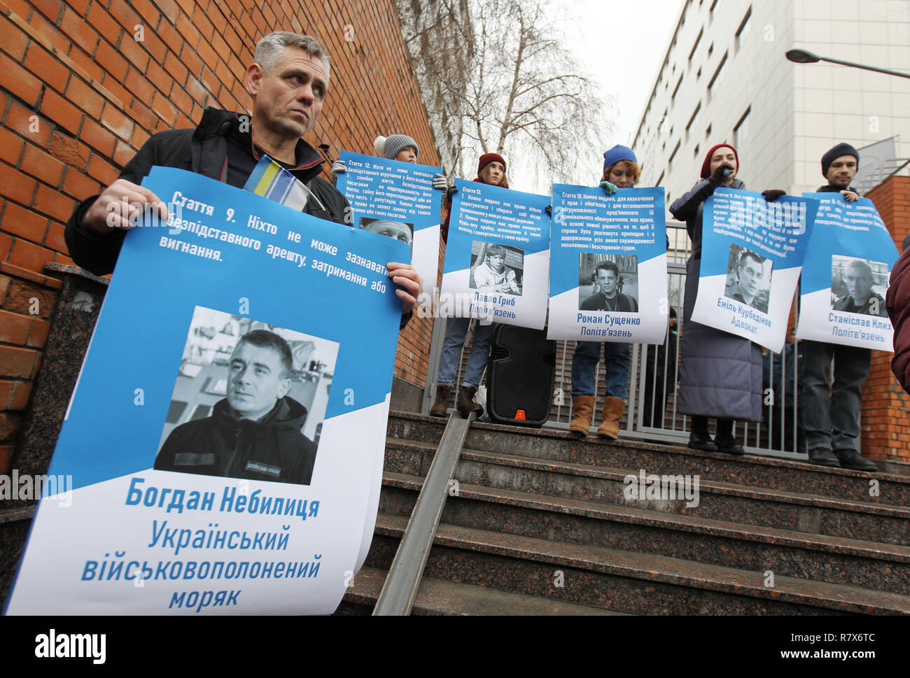 A man holding a placard with a portrait of Ukrainian navy sailor Bogdan Nebylitsa (L), seen before the activists holding placards with pictures of Ukrainian film director Oleg Sentsov and other 70 Ukrainian political prisoners jailed in Russia, including the sailors taken in the Azov Sea conflict, during the protest. Ukrainian film director Oleg Sentsov, who is convicted to 20 years in prison for 'plotting terrorist acts' in Russia-annexed Crimea, will be awarded for the 2018 Sakharov Prize for Freedom of Thought. The activists organised a rally at the embassy to remind the anniversary of the  Stock Photo