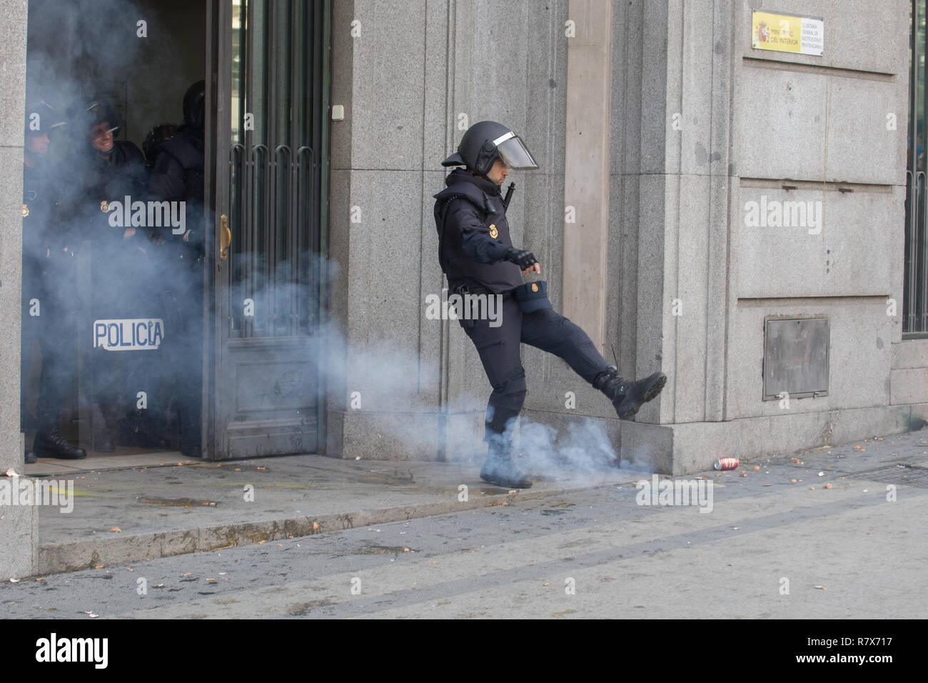 Riot police officer seen removing a firecracker from the door of the General Secretariat of Penitentiary Institutions of Spain during the protest. Hundreds of striking prison workers from all parts of Spain protest on the streets of Madrid to demand a salary improvement and an increase in the workforce. Stock Photo