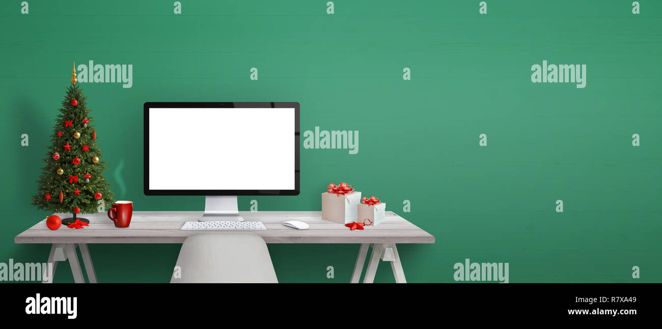 Computer display mockup with Christmas tree, gifts and decoration on desk. Free space beside on green wall for greeting text. Stock Photo