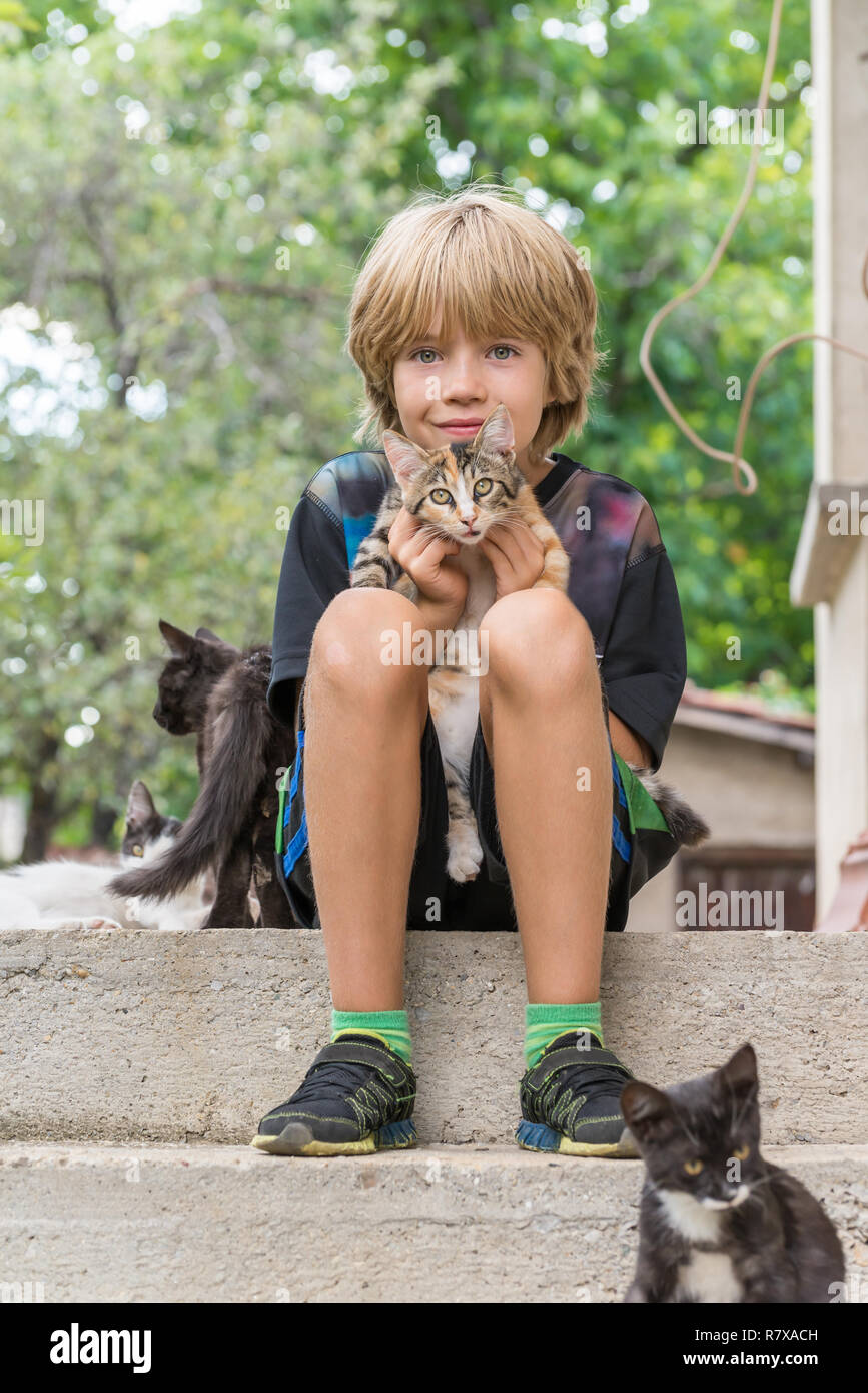 Adorable boy holding a kitten, sitting on stairs Stock Photo